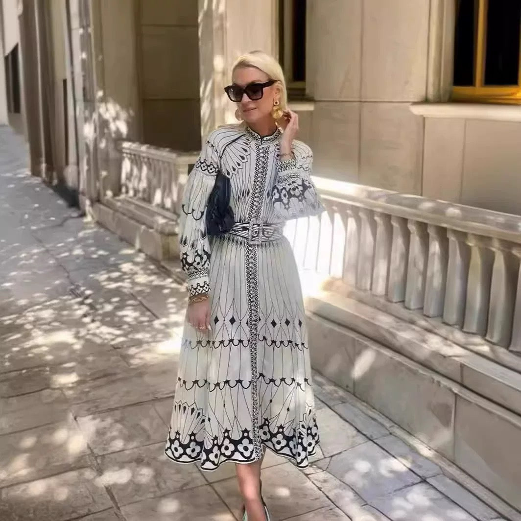Woman wearing Orchid Moda bohemian midi dress with black and white intricate patterns in outdoor urban setting
