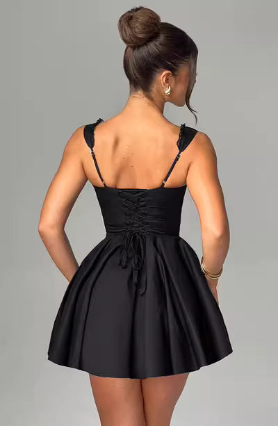 Back view of a woman wearing a cute mini dress for parties in black with lace-up back and ruffled straps