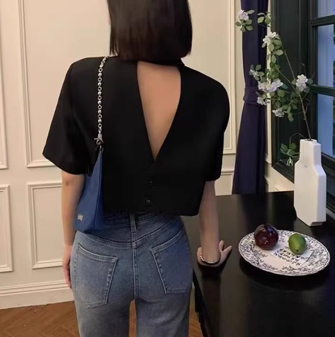 Orchid Moda black formal open back top worn with blue jeans by woman standing near table