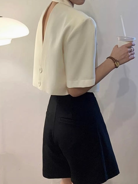 Orchid Moda formal open back top in white with short sleeves paired with black shorts