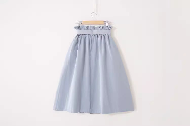 Light blue high waisted midi skirt for women with gathered waistband hanging on wooden hanger