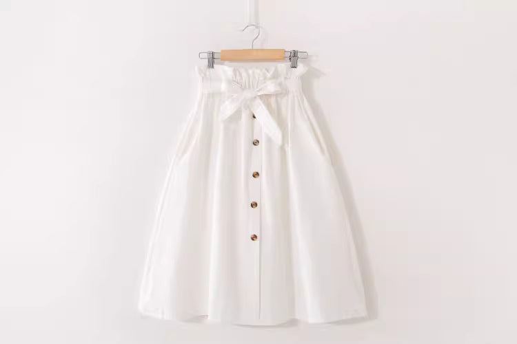 White high waisted midi skirt for women with front buttons and a tied waist belt hanging on a wooden hanger