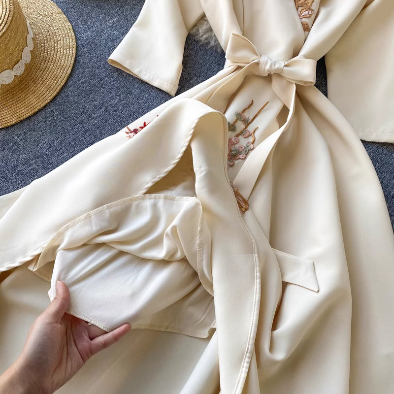 Hand holding the inner lining of a cream Almondine midi dress with floral embroidery from Orchid Moda