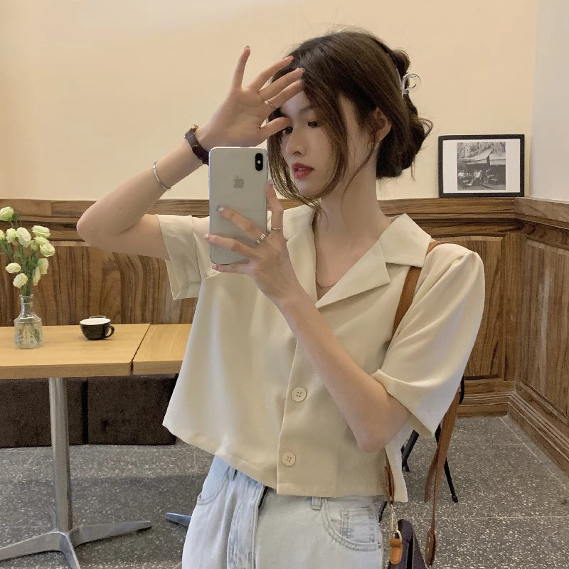 Woman wearing a trendy short sleeved shirt women in cream color taking a mirror selfie indoors