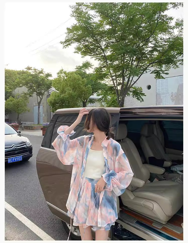 Woman wearing a flowy summer co ord set in pastel colors standing by an open car door outdoors