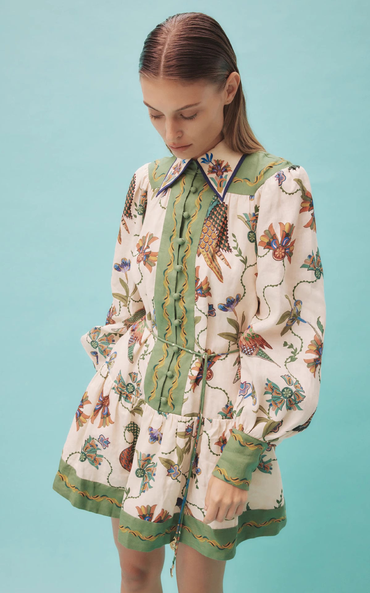 Orchid Moda peacock print lantern sleeve dress with green accents and floral details on model