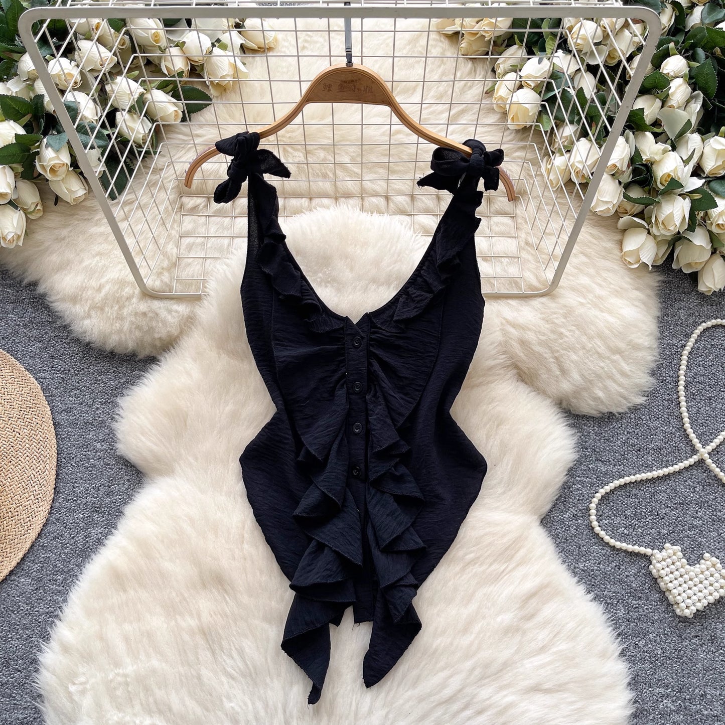 Black ruffled cami top for women with tie straps hanging on wooden hanger by Orchid Moda