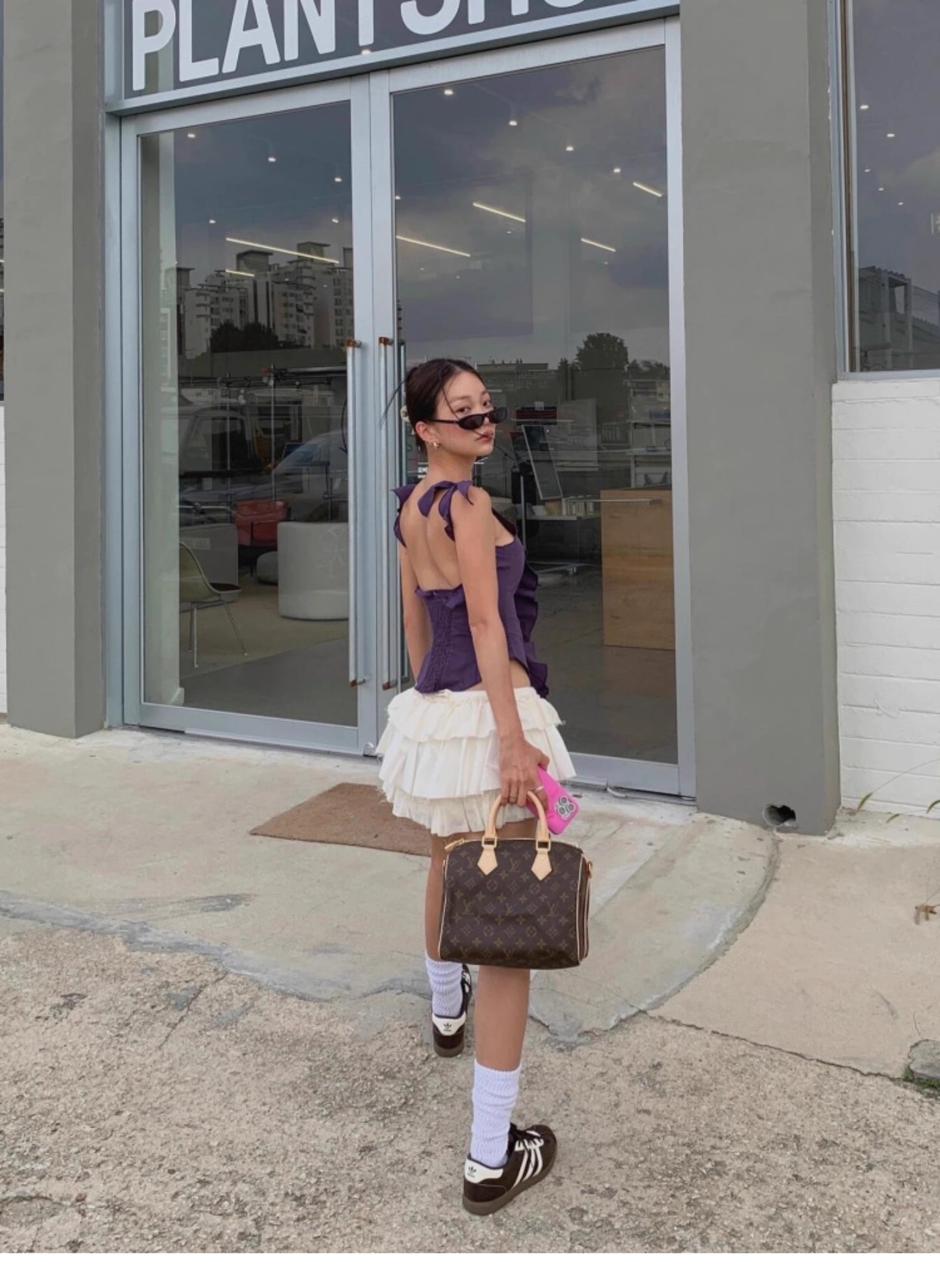 Woman wearing a purple ruffled cami top for women paired with white layered skirt and brown handbag
