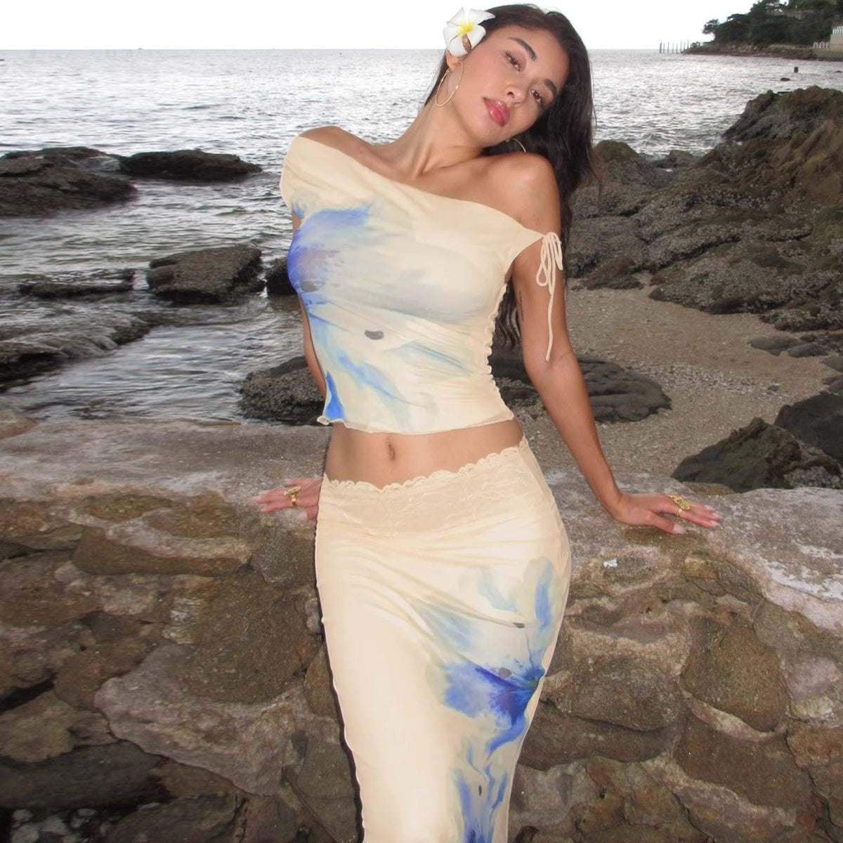 Orchid Moda beach vacation maxi skirt set featuring blue and beige off-shoulder top and matching flowing skirt by the rocky shore