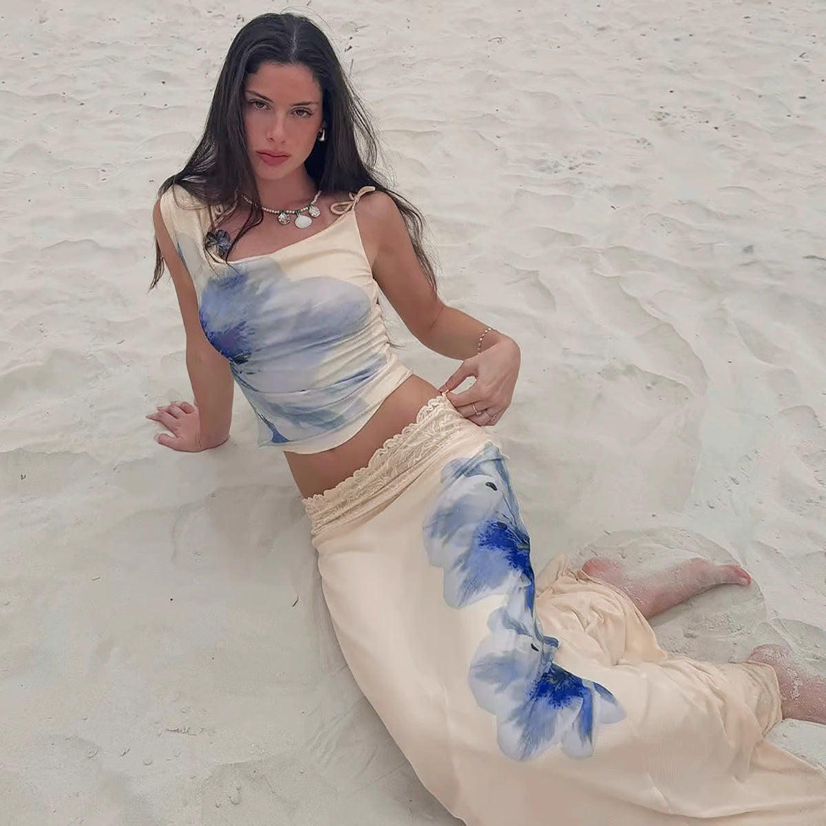 Orchid Moda beach vacation maxi skirt set featuring a cream top and skirt with blue floral prints on sand