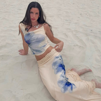 Orchid Moda beach vacation maxi skirt set featuring a cream top and skirt with blue floral prints on sand