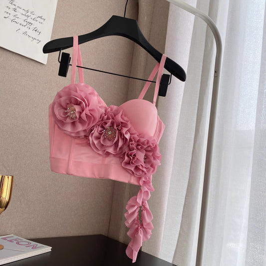 Orchid Moda blush corset top with large floral appliques and decorative bead accents hanging on black hanger