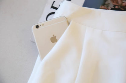 Close-up of white fabric with pocket holding a silver smartphone showcasing chic cold shoulder blazer dress details