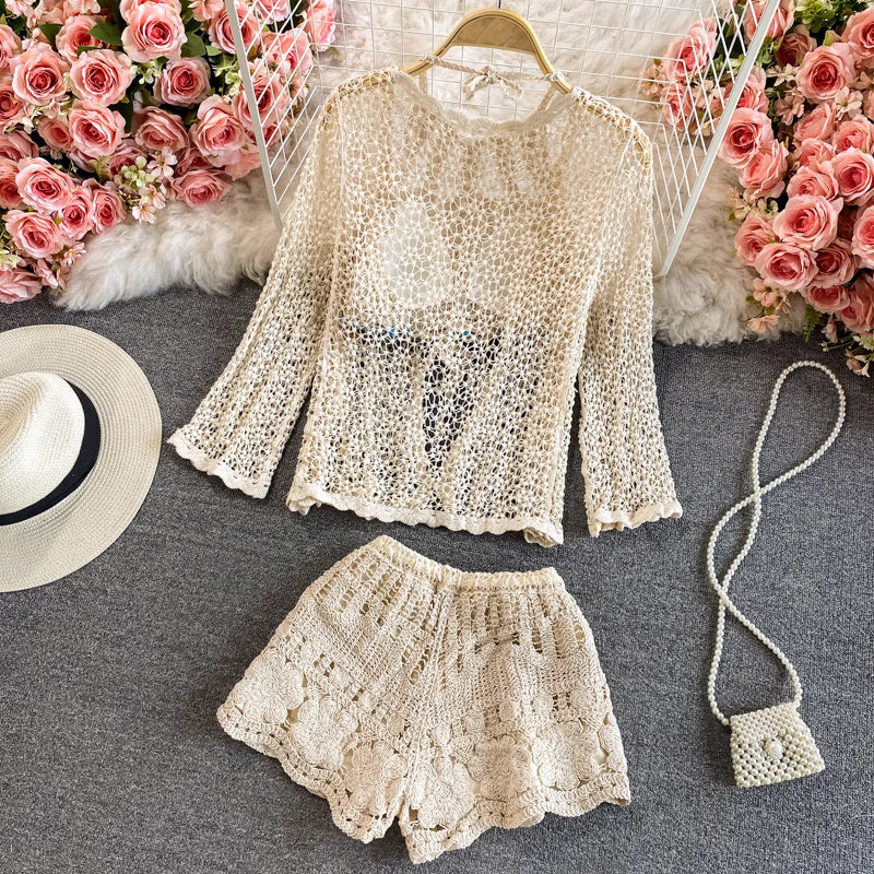 Orchid Moda crochet beachwear set with long sleeve top and shorts in beige displayed with a sun hat and small woven bag