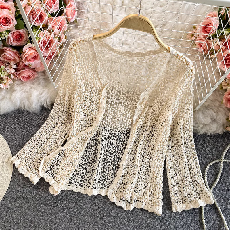 Orchid Moda beige crochet beachwear set top with scalloped edges displayed on hanger with flowers background