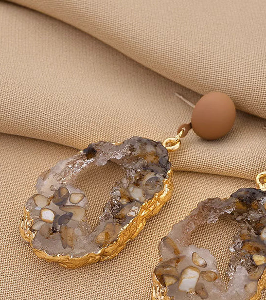 Orchid Moda trendy stone earrings for women with gold trim and natural stone pattern on beige fabric