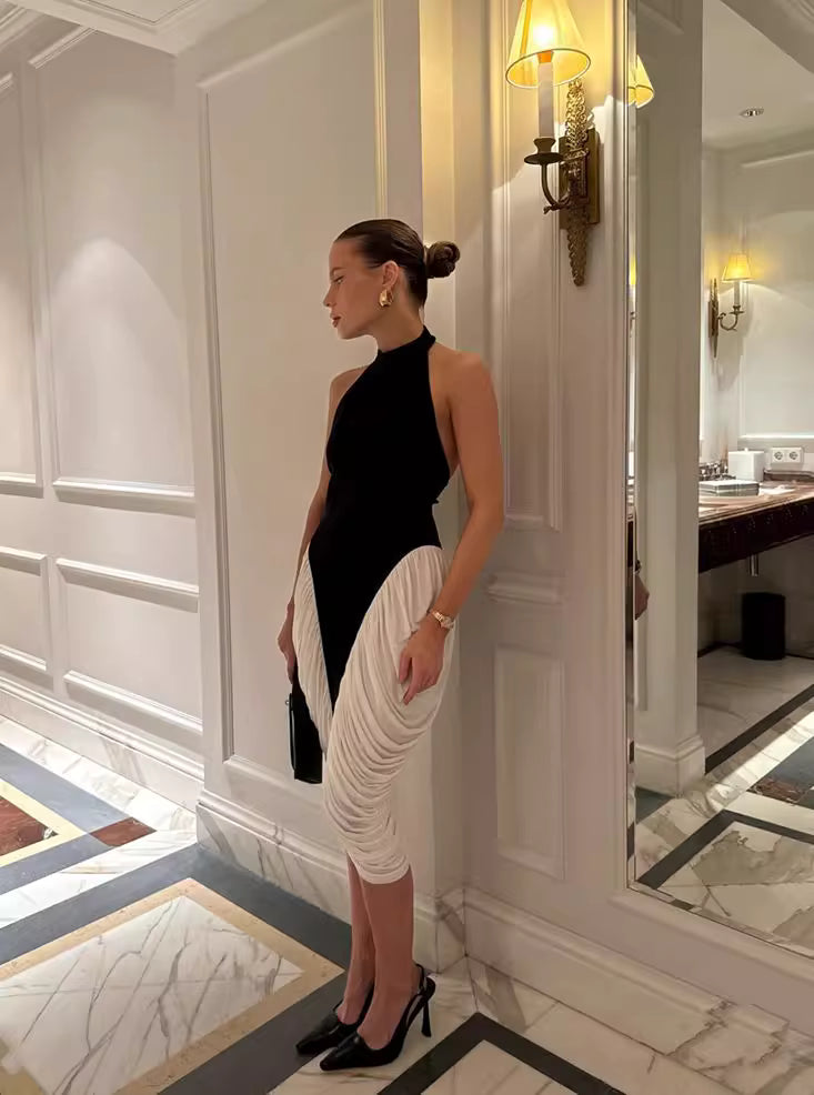 Woman wearing a black and white halter midi dress for women standing in an elegant hallway