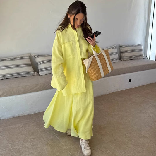 Woman wearing lemon yellow co ord set by Orchid Moda holding a woven tote bag and checking her phone