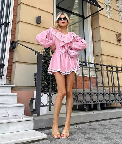 Woman wearing pink flare shorts and top set with ruffle details and long sleeves outdoors