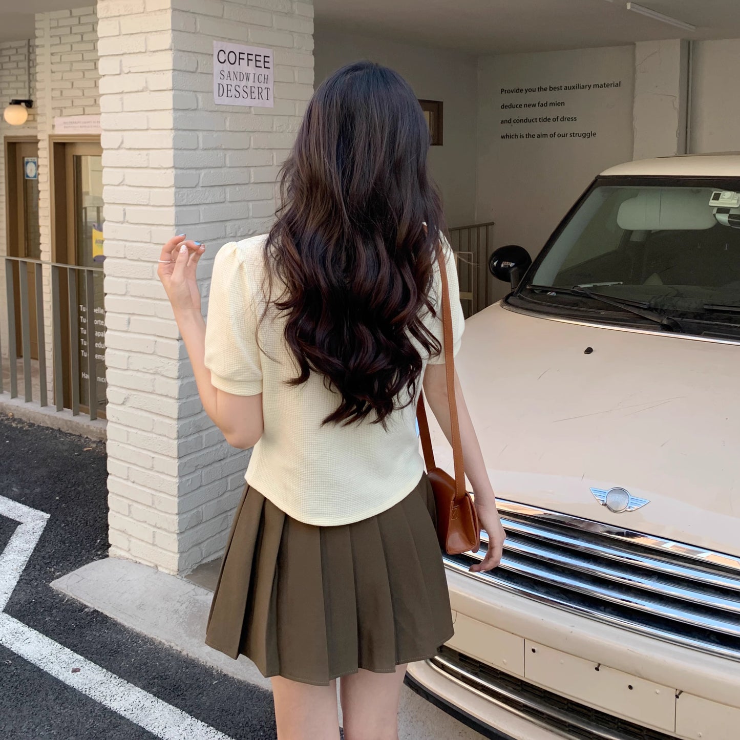 Orchid Moda short sleeve statement shirt in cream worn with a pleated skirt outdoors near a vintage car
