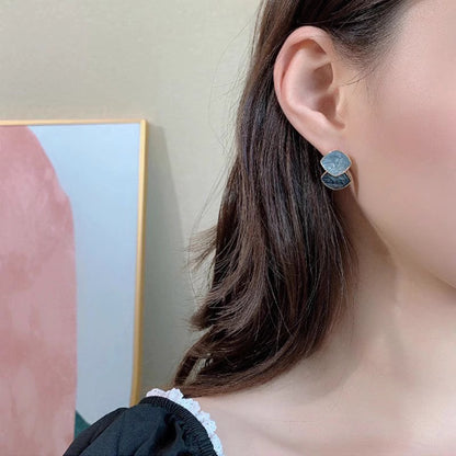 Close-up of trendy geometric earrings for women worn by a model with dark hair and a black top