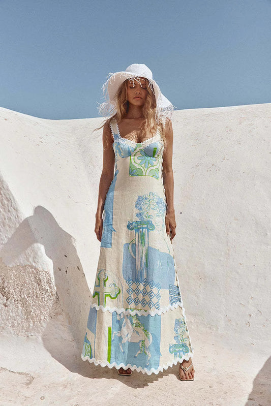 Orchid Moda trendy printed long dress in blue and green with a white sun hat on a sunny outdoor background