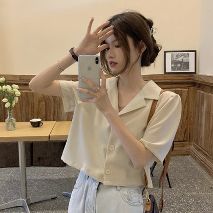Woman wearing a trendy short sleeved shirt women in cream color taking a mirror selfie indoors