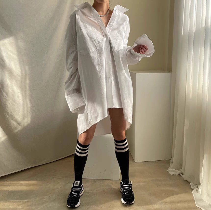 Woman wearing a white closet raid oversized shirt and skirt set paired with black knee-high socks and sneakers