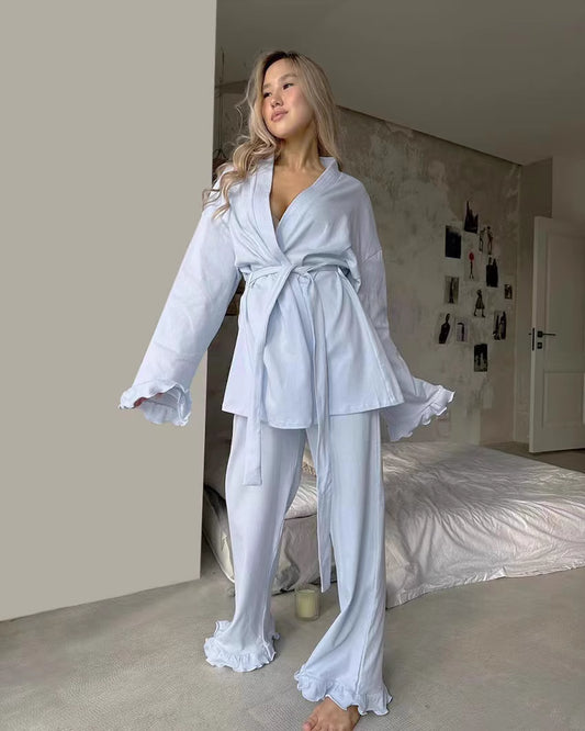 Woman wearing comfortable lounge wear pajamas in soft light blue with ruffled edges and a waist tie