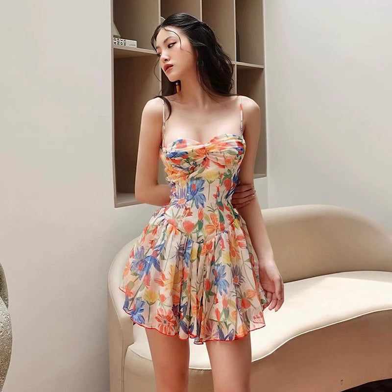 Woman wearing a colorful floral mini dress for women with thin straps standing indoors by a beige sofa