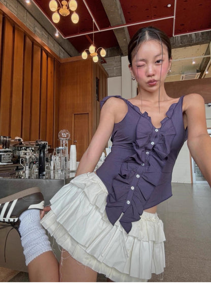 Woman wearing a purple ruffled cami top for women paired with a white layered skirt indoors