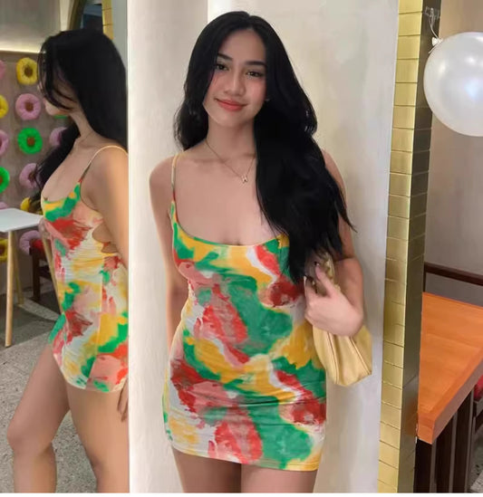 Woman wearing a colorful watermelon print bodycon dress with thin straps holding a yellow purse