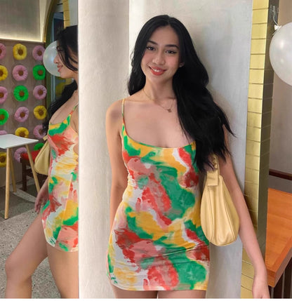 Woman wearing a colorful watermelon print bodycon dress carrying a yellow handbag indoors