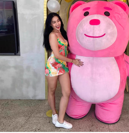 Woman wearing a colorful watermelon print bodycon dress standing next to a large pink bear mascot