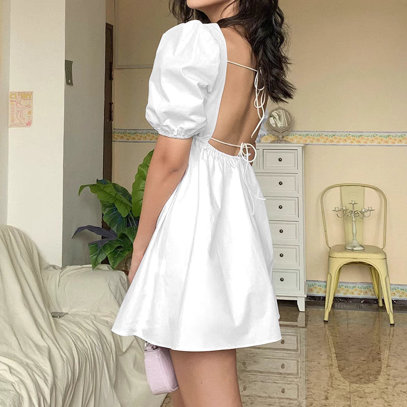 Orchid Moda white backless dress with puff sleeves and open back tie design on model indoors