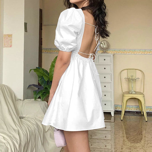 Orchid Moda white backless dress with puff sleeves and open back tie design on model indoors