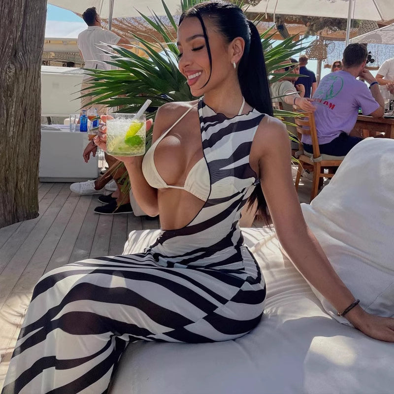 Woman wearing zebra print beachwear by Orchid Moda sitting on a white lounge chair holding a drink